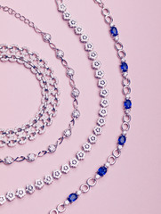 Set ot silver stylish necklaces isolated on light pink background. Jewelry pieces. Flat lay