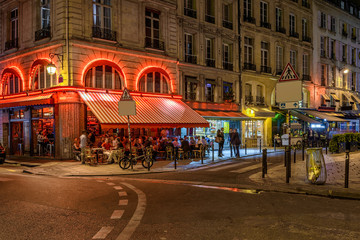 Naklejka premium Przytulna ulica ze stołami kawiarni w Paryżu w nocy, Francja