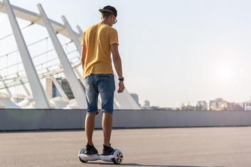 Full length young man riding on gyroscope. He turning back to camera. Copy space