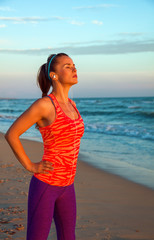 woman on seashore at sunset with headphones listening to music