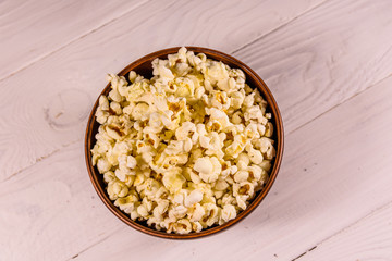 Ceramic bowl with popcorn on wooden table. Top view