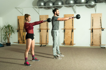 Fototapeta premium Young couple kettle bell fitness exercise in the gym, selective focus
