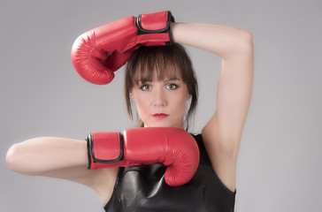 Woman wearing a black leather top and red boxing gloves