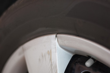 Silver car tire rim is broken and scratched because of hitting something, cracked, needed to...