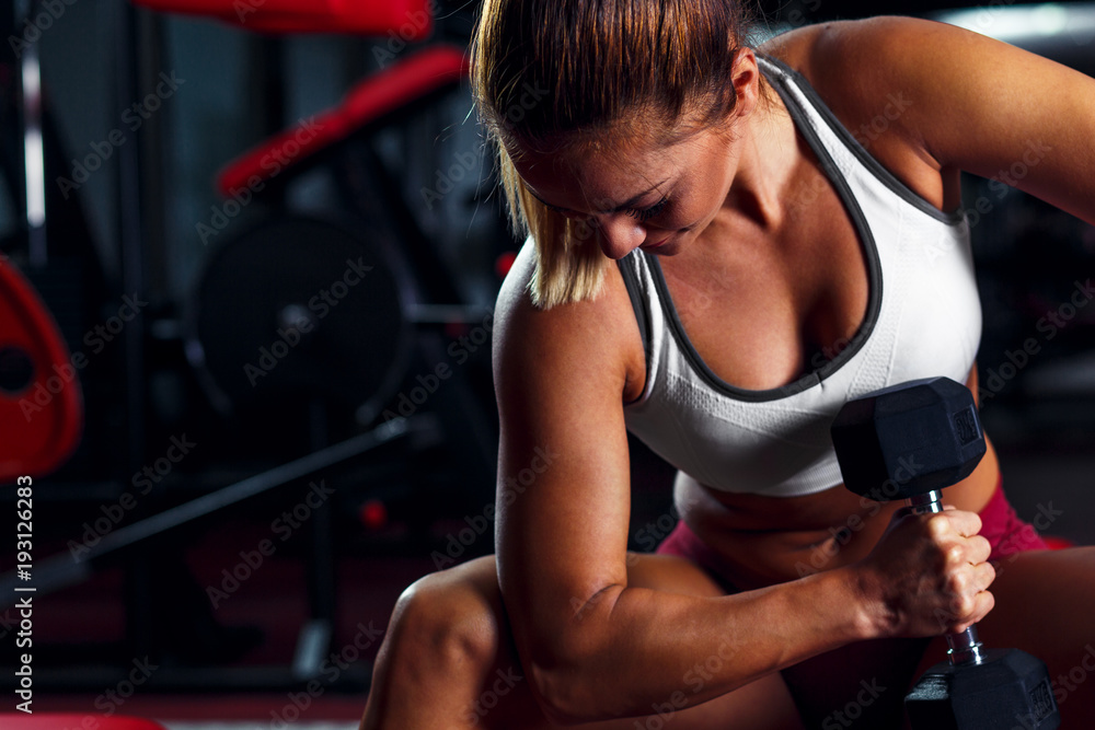 Wall mural Young woman exercising with weight in the gym.