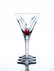 Three martini glasses in a row with a red cherrie in the first glass against an all white background