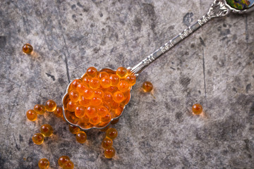 Delicious bright red fresh snack red caviar on a wooden background. Silver spoon with caviar. Expensive luxury delicacy seafood.