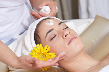 Fototapeta na wymiar Female Enjoying Relaxing face Massage In Cosmetology Spa Center