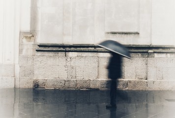 blurry person walks in town with rain