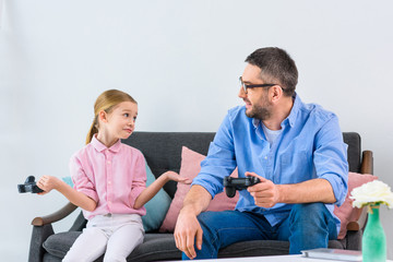 daughter and father playing video game together at home