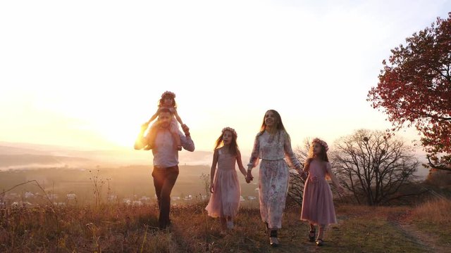 Happy young luxury dressed family walking in the autumn park during sunset.