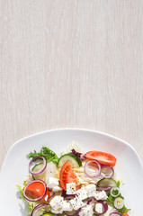 Fresh spring salad with cucumber, tomato, cheese and arugula isolated on a white plate 