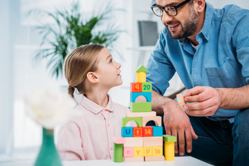 portrait of family building pyramid from colorful blocks at home