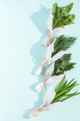 Bunches bouquets of fresh greens for salad packed in white paper on a blue background isolated 
