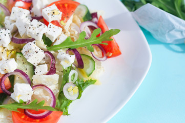 Fresh spring salad with cucumber, tomato, cheese and arugula isolated on a white plate 