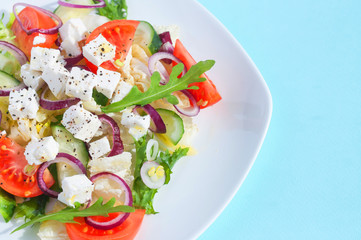 Fresh spring salad with cucumber, tomato, cheese and arugula isolated on a white plate 