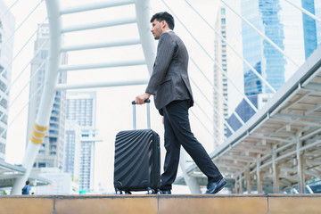 Business man walking at outdoors with luggage in the routine of working with determination and confidence. concept of business trip travel and transportation.