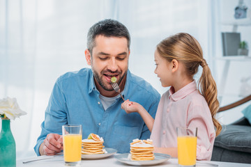Fototapeta na wymiar portrait of father and little daughter having breakfast together at home