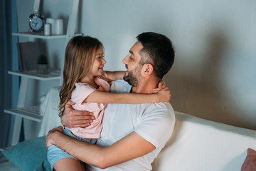 side view of smiling father and daughter looking at each other at home