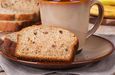 Slice of banana nut bread and coffee cup on a plate