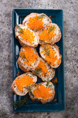 Delicious bright red fresh snack red caviar on a wooden background. Silver spoon with caviar. Expensive luxury delicacy seafood.