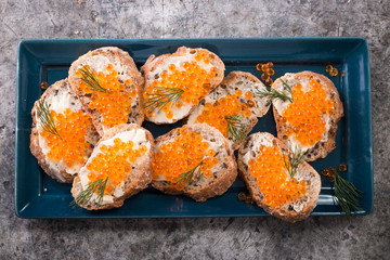 Delicious bright red fresh snack red caviar on a wooden background. Silver spoon with caviar. Expensive luxury delicacy seafood.