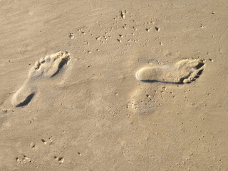 Two tracks of human feet on the sand.