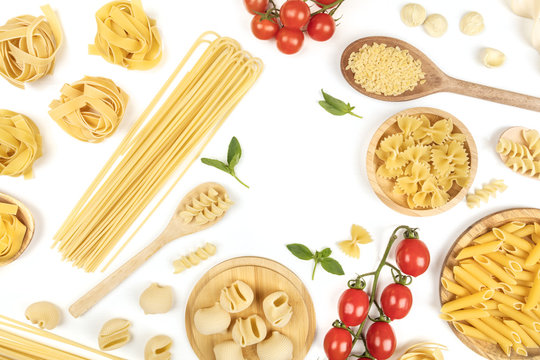 Overhead photo of different types of pasta with tomatoes and basil on white with copy space