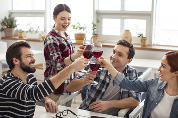 Celebrating. Beautiful joyful dark-haired young woman smiling and drinking wine with her friends and celebrating