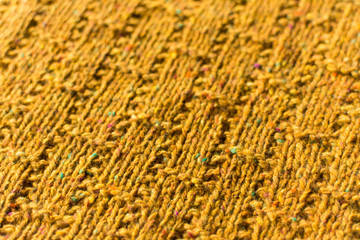 Crafted background: close up perspective view of mustard color knitted pattern swatch