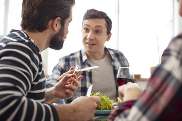 So tasty. Cheerful young friends sitting at the table and enjoying their lunch while having a pleasant talk