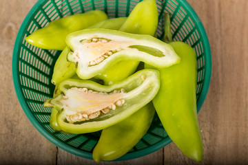 Green peppers in a basket on a wooden floor.