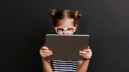Cute child with digital tablet. Portrait of pretty little girl using web app for education. 