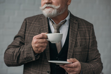 cropped shot of senior man with cup of coffee