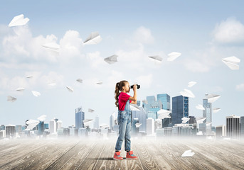 Concept of careless happy childhood with girl looking in binoculars