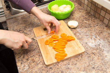 A girl is cutting a carrot with a knife on the board