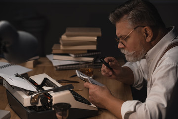 senior writer reading manuscript in notebook with magnifying glass