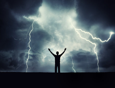 Man silhouette on a storm background. Lord of the lightning. Background on the theme of survival, philosophy, religion.