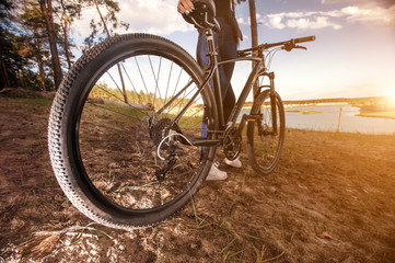 Fototapeta na wymiar Sunset vacation. Fat bike also called fatbike or fat-tire bike in summer riding in the forest. The rider rides a bicycle among trees and stumps. Overcomes some obstacles on a bumpy road.