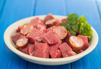 raw meat with smoked sausages on plate