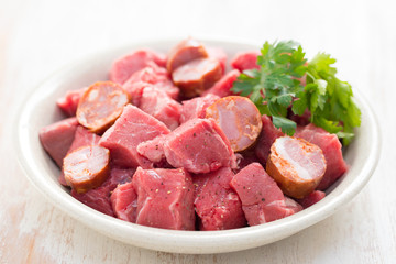 raw meat with smoked sausages on plate