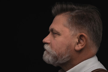 side view of senior man with stylish beard isolated on black