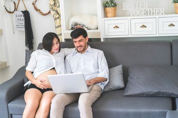 The pregnant woman encourages her husband who is working in the living room at home.