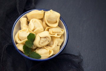 ravioli in beautiful bowl on black ceramic background
