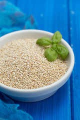 uncooked quinoa in white bowl on white wooden background