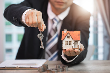 Businessman signs contract behind home architectural model