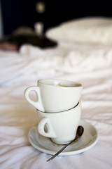 empty cups of coffee on an unmade bed