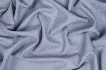 Fototapeta premium Blue woolen crumpled wrinkled fabric with waves, background crumpled tissue.