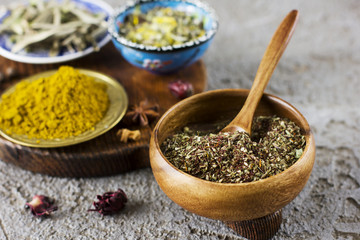 Different dry spices in bowls on a wooden Board on a concrete background