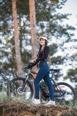 Fototapeta na wymiar Great beginning of the day. Sexy shapely girl in cap ride a bicycle.Woman outdoors in nice spring park, wearing jacket and trendy sports outfit, sneakers, smiling